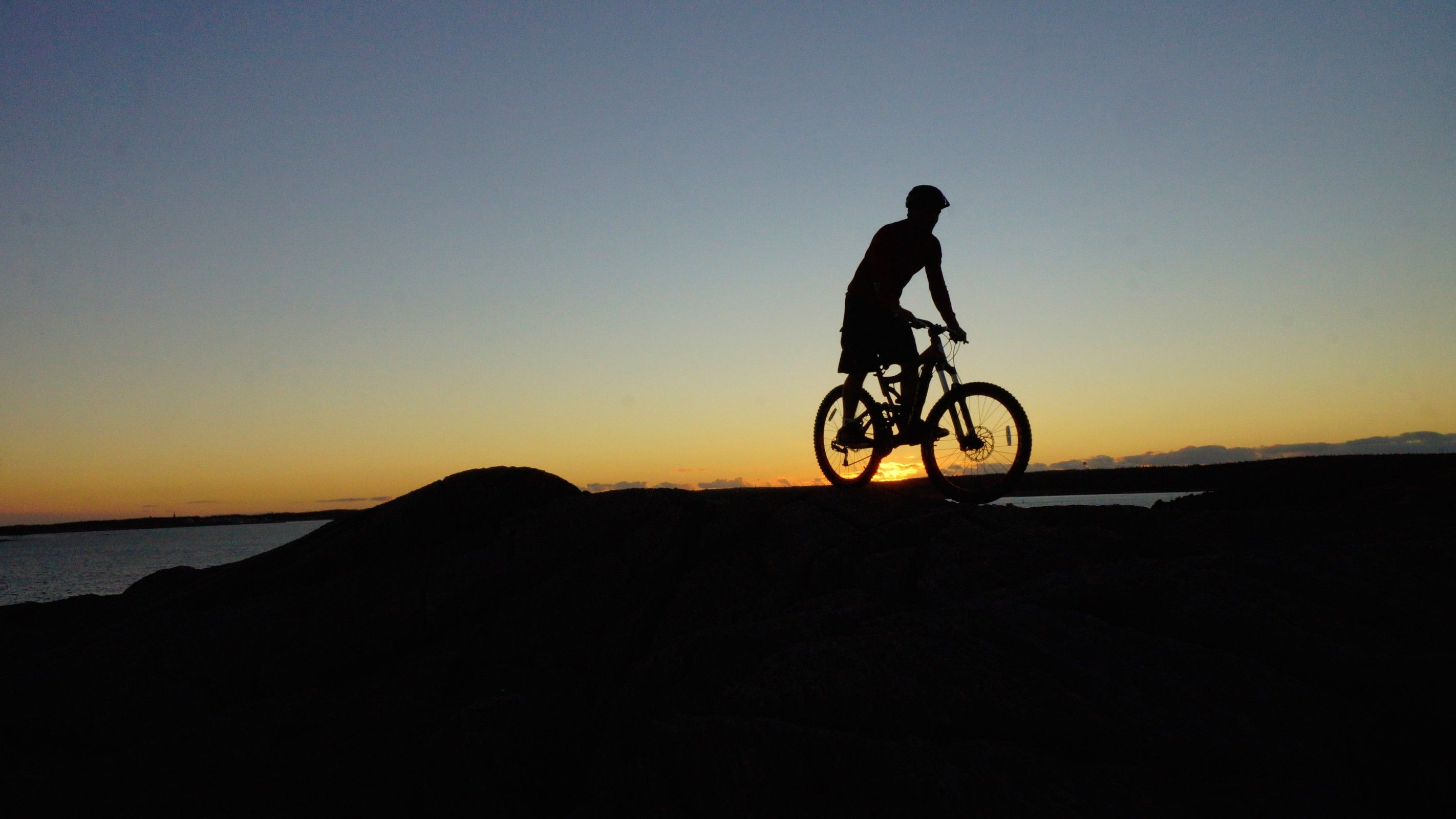 Mountain biker pedalling across rocks in Louisbourg, Cape Breton Island, Nova Scotia, Canada